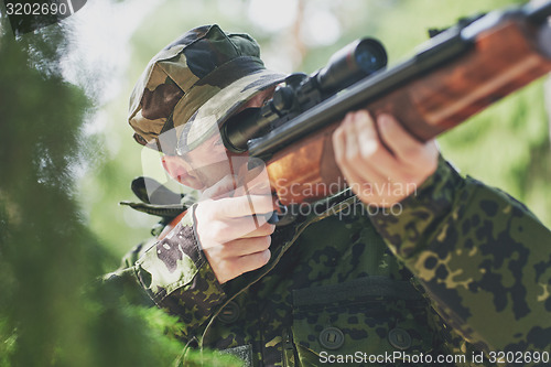 Image of soldier or hunter shooting with gun in forest