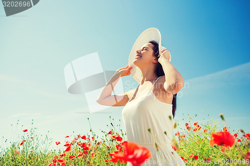 Image of smiling young woman in straw hat on poppy field