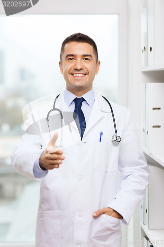 Image of smiling doctor making handshake at medical office