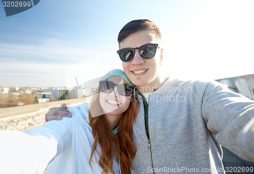 Image of happy teenage couple taking selfie on city street