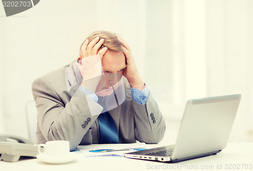 Image of upset older businessman with laptop and telephone