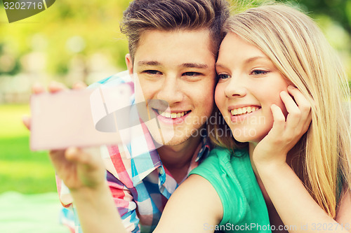 Image of smiling couple making selfie in park