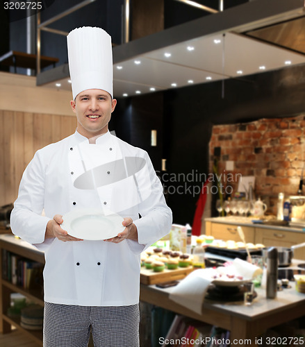 Image of happy male chef cook showing empty plate