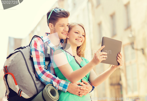 Image of smiling couple with tablet pc and backpack in city