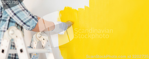 Image of close up of male in gloves painting a wall