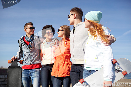 Image of happy teenage friends with longboards on street