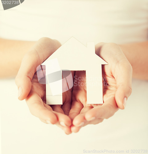 Image of woman hands holding paper house