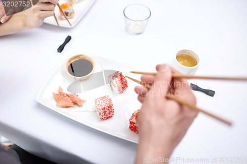 Image of close up of couple eating sushi at restaurant