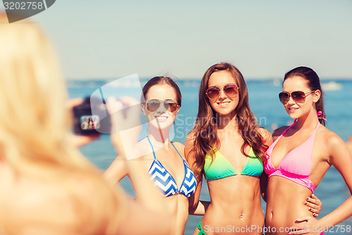 Image of group of smiling women photographing on beach