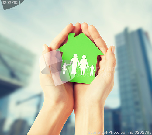 Image of hands holding green house with family
