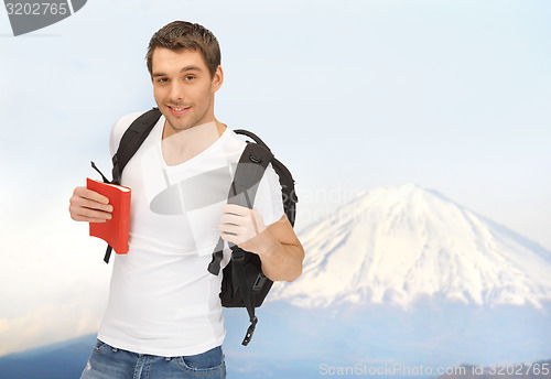 Image of happy young man with backpack and book travelling