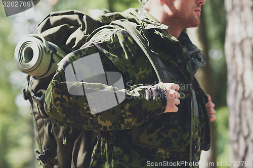 Image of close up of young soldier with backpack in forest