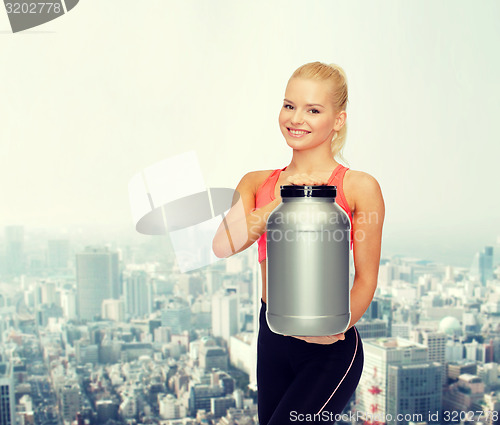 Image of smiling sporty woman with jar of protein