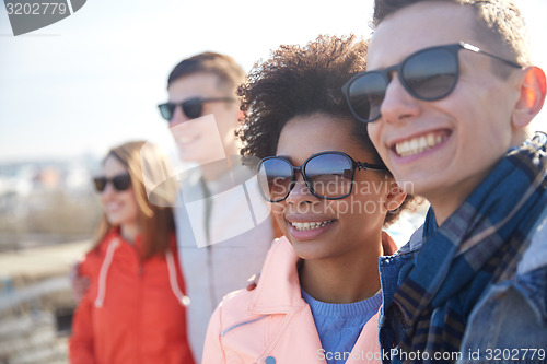 Image of happy teenage friends in shades hugging on street