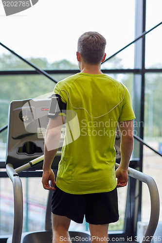Image of man exercising on treadmill in gym from back