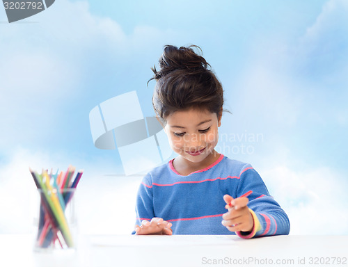 Image of happy little girl drawing with coloring pencils