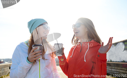 Image of happy teenage girls with coffee cups on street