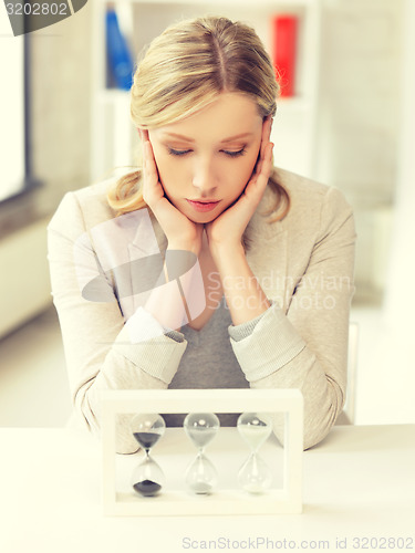 Image of pensive businesswoman with sand glass