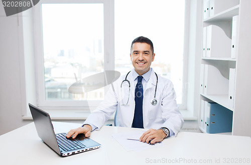 Image of smiling male doctor with laptop in medical office