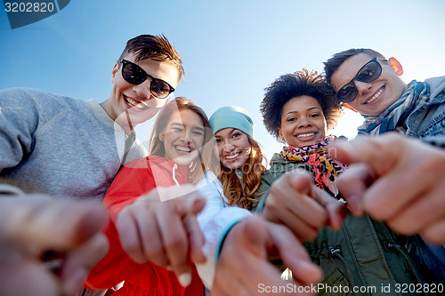 Image of happy teenage friends pointing fingers on street