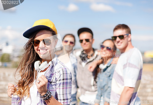 Image of teenage girl with headphones and friends outside