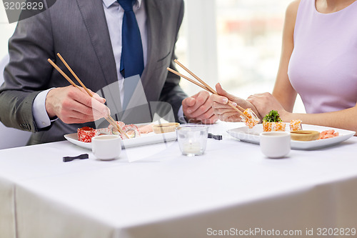 Image of close up of couple eating sushi at restaurant