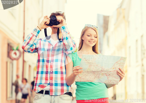 Image of smiling couple with map and photo camera in city