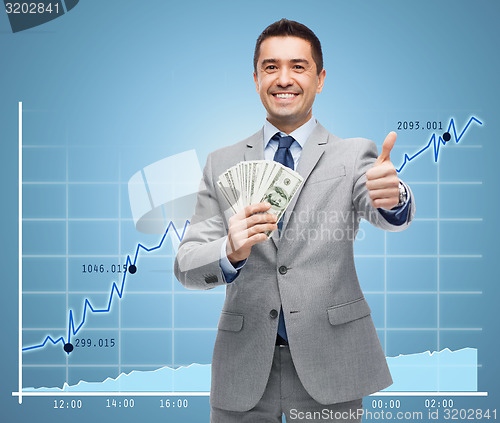 Image of smiling businessman with money showing thumbs up