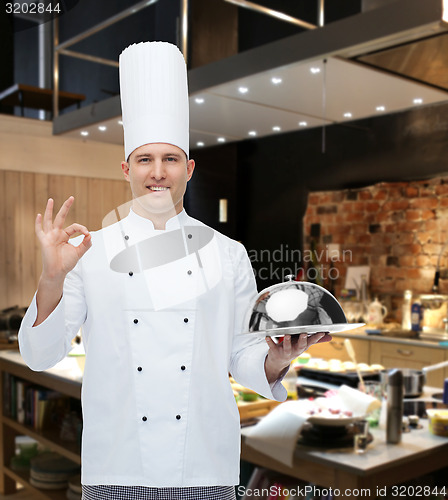 Image of happy male chef cook with cloche showing ok sign