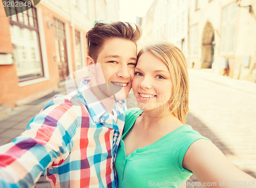 Image of smiling couple with smartphone in city