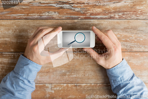 Image of close up of hands with magnifier on smartphone