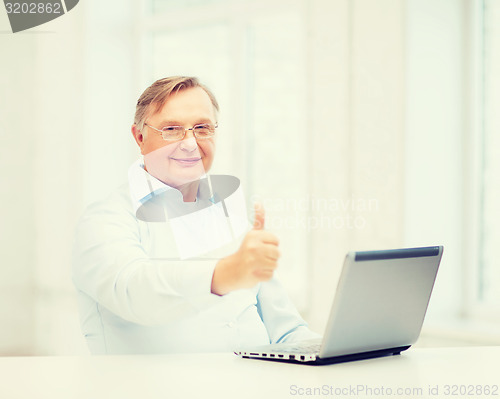 Image of old man with laptop computer showing thumbs up