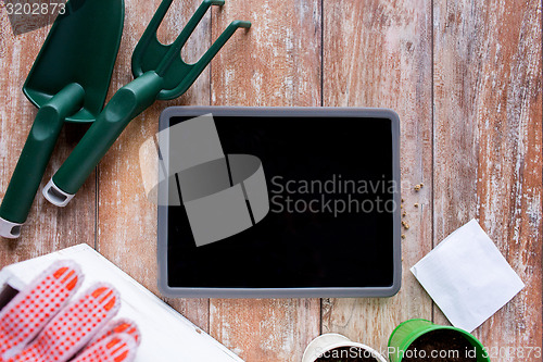 Image of close up of tablet pc and garden tools on table