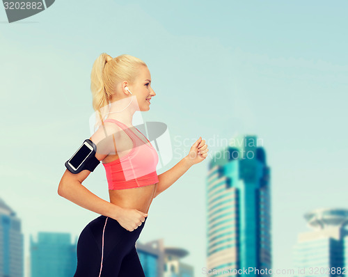 Image of sporty woman running with smartphone and earphones