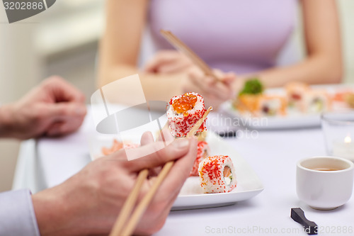 Image of close up of couple eating sushi at restaurant