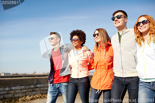 Image of happy teenage friends walking along city street