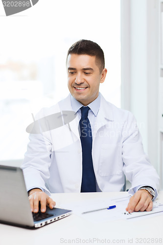Image of smiling male doctor with laptop in medical office