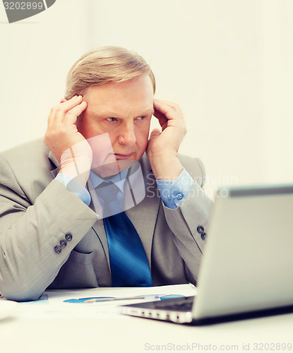 Image of upset older businessman with laptop in office