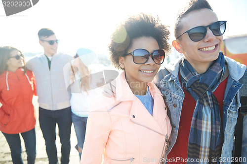 Image of happy teenage friends in shades hugging on street