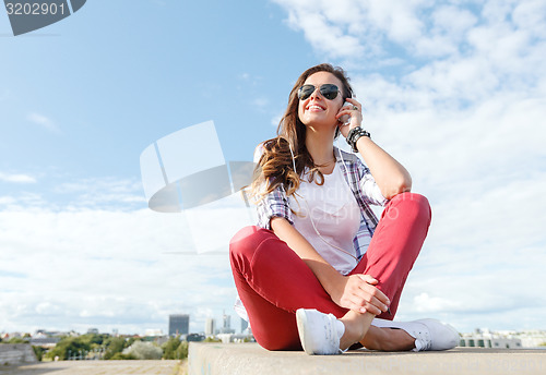 Image of smiling teenage girl in eyeglasses with headphones