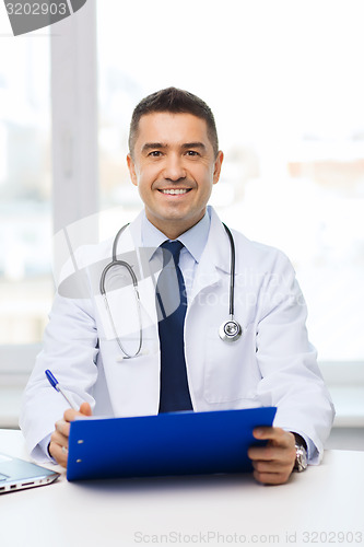 Image of happy doctor with clipboard in office