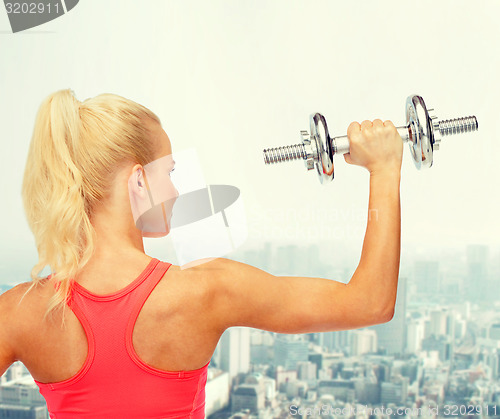 Image of sporty woman with heavy steel dumbbell from back