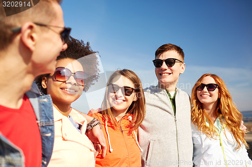 Image of happy teenage friends in shades talking on street