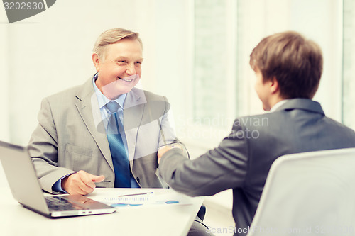 Image of older man and young man shaking hands in office