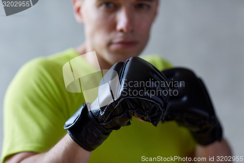 Image of young man in boxing gloves indoors