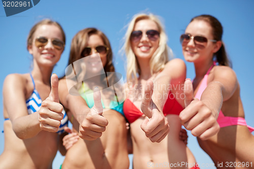 Image of group of smiling young women on beach