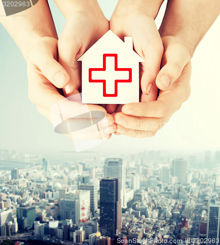 Image of hands holding paper house with red cross