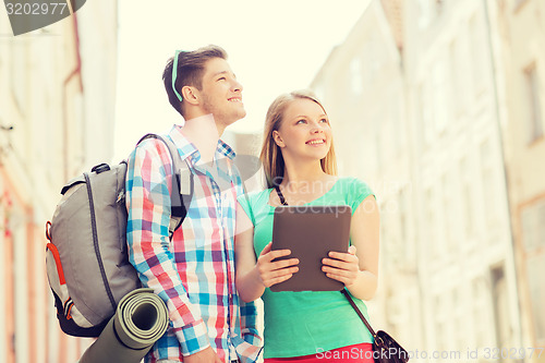 Image of smiling couple with tablet pc and backpack in city