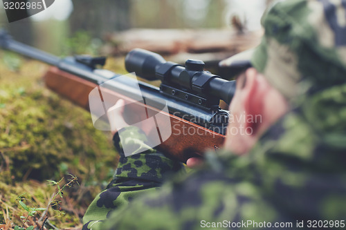 Image of soldier or hunter shooting with gun in forest