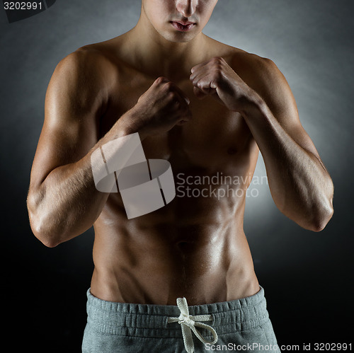 Image of young man on fighting stand over black background